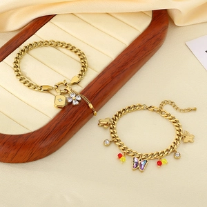 Detail of gold chain bracelets with purple butterfly and diamond flower on velvet tray