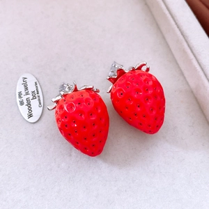 Detailed close-up of red strawberry stud earrings with silver leaves and sparkling zircon
