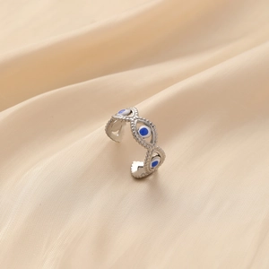 Detail shot of silver stainless steel open ring with blue and white eye motifs on silk