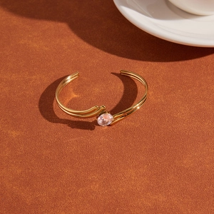Detail of gold-plated titanium steel open bangle featuring a large sparkling zircon stone