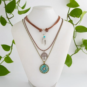 Detail of layered bohemian necklace with feather, tree of life, and mandala charms