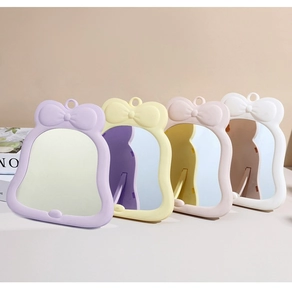 Dettaglio di specchi da trucco portatili in viola, giallo, rosa e bianco con fiocco decor