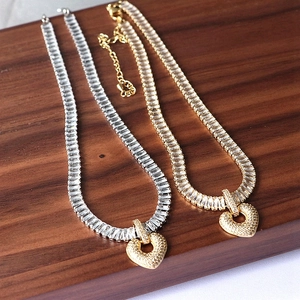 Close-up of gold and silver heart pendant necklaces with rectangular zircon stones