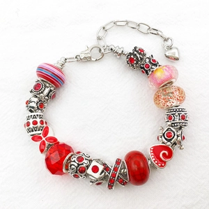 Detail of DIY bracelet featuring red faceted glass beads and silver alloy charms
