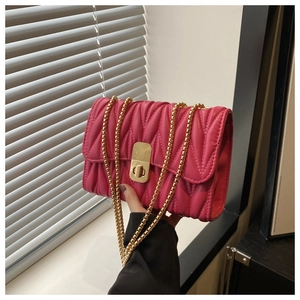 Close-up of fuchsia matelassé quilted chain bag with gold rectangular turn-lock closure