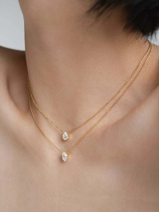 Close-up of double layered gold chains with pear and oval cut zircon pendants on model