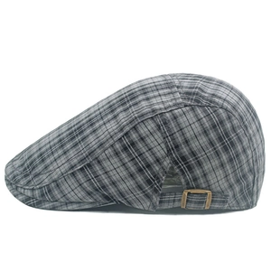 Détail de casquette gavroche à carreaux gris avec boucle de réglage en bronze sur le côté