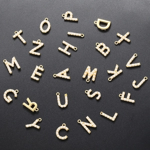 Close-up of 18K gold plated alphabet pendants featuring delicate inlaid pearls