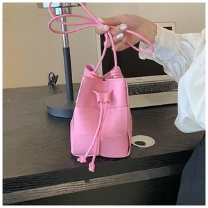 Close-up of pink woven bucket bag featuring detailed drawstring closure and wide straps