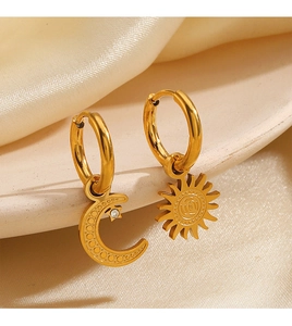 Macro shot of gold sun and moon mismatched earrings with rhinestones on silk