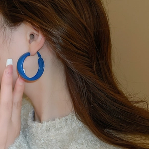Close-up of minimalist Klein blue C-shaped hoop earrings worn on a model for a chic style