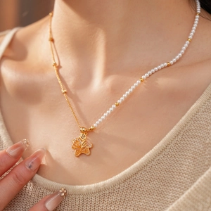 Detail of 18k gold plated necklace with pearls and zircon-encrusted winged star pendant