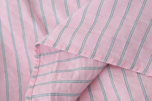 Vue macro du tissu rose à rayures bleues montrant la texture et les détails de couture
