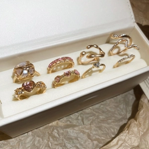 Detailed view of an 8-piece gold ring set with pink heart stones and pearls in a jewelry box