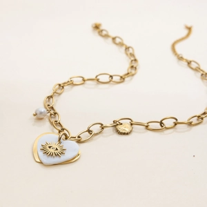 Detail of gold chain necklace featuring a pearl and double heart pendant with eye motif