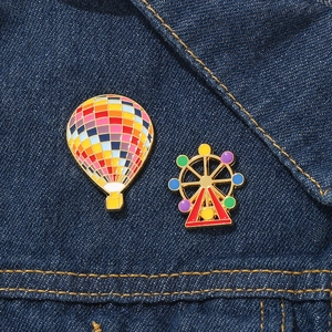 Colorful enamel hot air balloon and Ferris wheel brooch pins on blue denim jacket