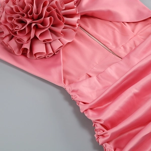 Gros plan sur les fleurs 3D faites main et les plis élégants d'une robe en satin rose