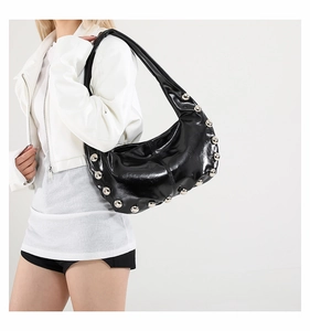 Detailed side view of black patent leather hobo bag featuring large silver metal rivets