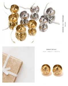 Detailed view of gold and silver hollow sphere earrings with zircon hearts on a mirror