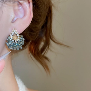 Gros plan d'une boucle d'oreille vintage française avec cristal ambre et perles bleu-gris