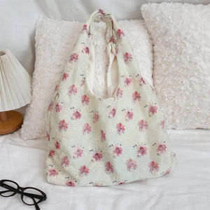Close-up of floral embroidery on a cream canvas tote bag in a cozy bedroom setting