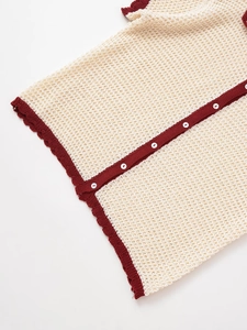 Detail of knit set showing hollow texture, contrast trim and white round buttons