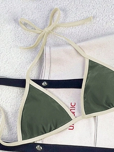 Detail of dark green triangle bikini top with cream binding and halter neck tie strings