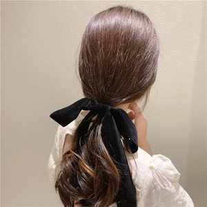 Elegant black velvet long bow hair scrunchie shown tied on a low ponytail