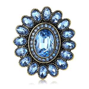 Elegante spilla girasole in cristallo blu con montatura in oro antico su fondo bianco