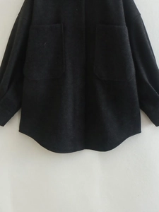 Gros plan sur la veste en laine noire avec de grandes poches poitrine et un ourlet arrondi