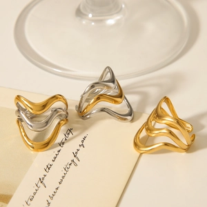 Close-up of minimalist layered wave rings in gold and two-tone finish on vintage display