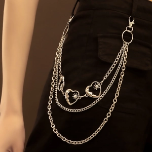 Detail of silver multi-layer metal waist chain with heart and star charms on jeans