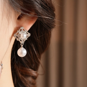 Detail of silver drop earring with geometric hollow diamond pattern and elegant white pearl