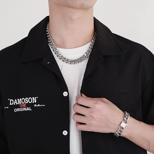 Close-up of a silver-tone Cuban link necklace and bracelet set on a male model