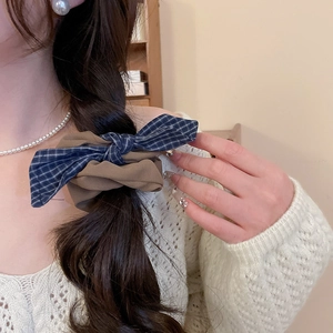 Detail of blue grid and khaki bow scrunchie styled on a braided hairstyle