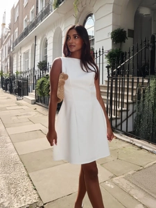 Elegant sleeveless white A-line dress with slim fit waist and pleated hem detail