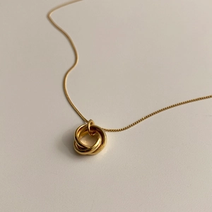 Macro shot of interlocking triple-ring gold pendant on a minimalist thin chain
