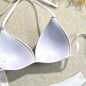Close-up of bikini top detail with size S care label on a woven texture background