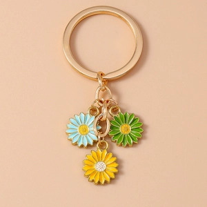 Detail view of gold keychain featuring blue, green, and yellow enamel daisy charms