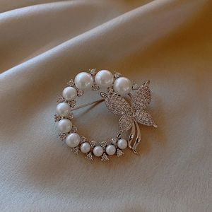 Elegant silver butterfly brooch with pearls and crystals on beige silk background