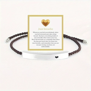 Close-up of woven rope bracelet with 'Just breathe' engraved metal bar on a gift card