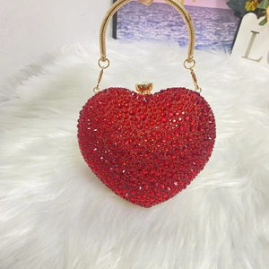 Close-up of red heart-shaped rhinestone clutch bag with gold round metal handle