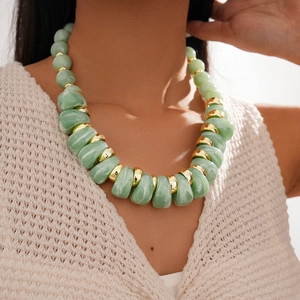 Close-up of chunky green marbled acrylic beads with gold metal spacers on model