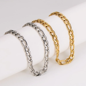 Polished 11mm gold and silver Figaro link necklaces displayed on a white cylindrical stand