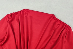 Close-up of red ruched dress fabric showing glossy texture and detailed pleats