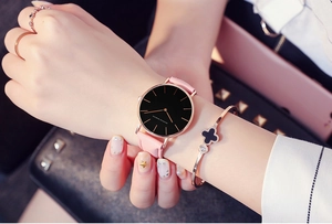 Minimalist quartz watch with pink leather strap and clover bracelet on model wrist