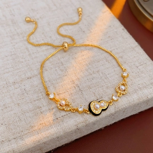 Detailed macro view of gold-plated bracelet with black heart enamel and pearls