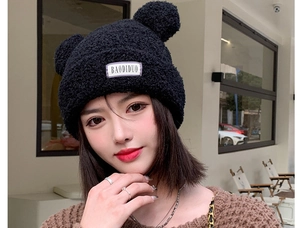 Detailed close-up of cute bear ears and thick plush texture on a black winter knit hat