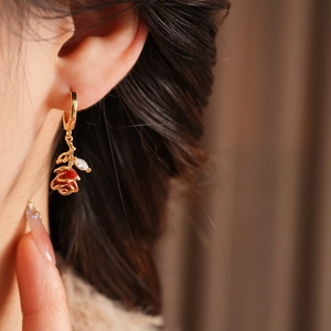 Gros plan sur une boucle d'oreille rose rouge élégante avec feuilles en zircon