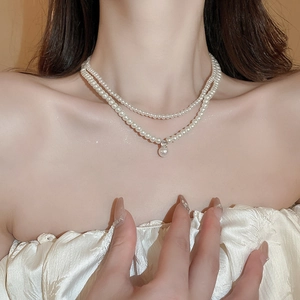 Detail of elegant double-layered pearl necklace with a large round pendant on neck